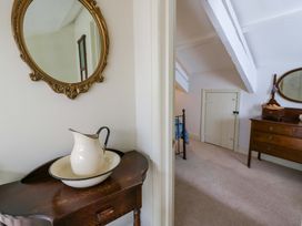 A bedroom with a mirror and a pitcher on a table at Rose Cottage St Dogmaels near Cardigan