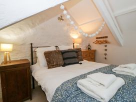A bedroom with a bed, lamp, and dresser at Rose Cottage St Dogmaels near Cardigan