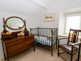 A nursery with a crib and dresser at Rose Cottage in St Dogmaels near Cardigan