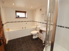 A bathroom with a bath tub, shower, toilet, and sink at Stable Cottage in Bolton Low Houses