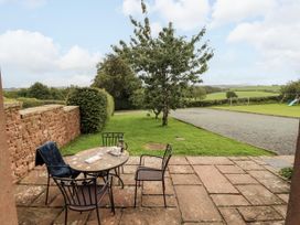 A table and chairs on a patio overlooking the garden at Stable Cottage in Bolton Low Houses