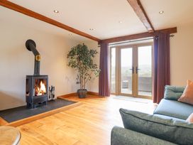 A living room with a wood stove and double doors at Ty Gwyn Llangwm near Bala