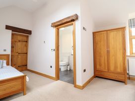 A bedroom with a bed and wardrobe leading to a bathroom at Ty Gwyn in Llangwm near Bala