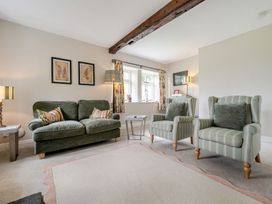 A living room with a sofa, armchairs, and a table at Dove Cottage at the Graythwaite Estate near Hawkshead