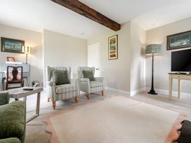 A living room with armchairs and a television at Dove Cottage at the Graythwaite Estate near Hawkshead