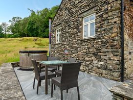 An outdoor seating area with a hot tub and a table with chairs at Dove Cottage at the Graythwaite Estate near Hawkshead