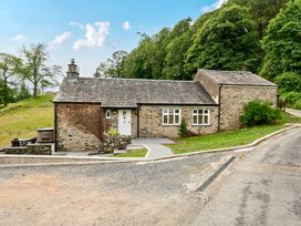 A stone house with a pathway and trees at Dove Cottage at the Graythwaite Estate near Hawkshead