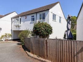 A white two story house with a tiled roof and a wooden fence around a small garden at Moorside in Horrabridge near Tavistock