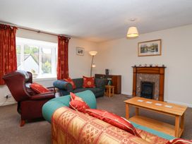 A living room with sofas a coffee table a fireplace and red curtains at Moorside in Horrabridge near Tavistock
