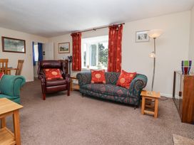 A living room with patterned sofa and armchair with red cushions and a tall lamp at Moorside in Horrabridge near Tavistock
