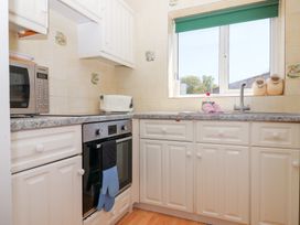 A kitchen with white cabinets a stove microwave toaster and a window at Moorside Horrabridge near Tavistock