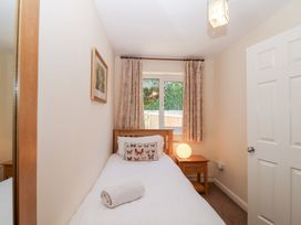 A single bedroom with a bed pillow and rolled towel bedside table with lamp window with curtains at Moorside in Horrabridge near Tavistock