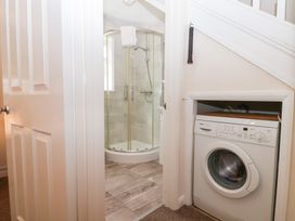 A washing machine under stairs next to a bathroom with a curved glass shower at Moorside in Horrabridge near Tavistock
