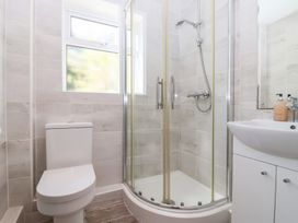 A bathroom with a toilet shower enclosure with glass doors and a sink with cabinet at Moorside Horrabridge near Tavistock