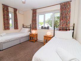 A bedroom with two single beds bedside tables lamps and patterned curtains at Moorside Horrabridge near Tavistock