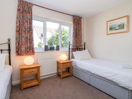 A bedroom with two single beds two bedside tables with lamps and a window with curtains at Moorside in Horrabridge near Tavistock
