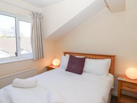 A bedroom with a double bed two bedside tables with lamps and a window with curtains at Moorside in Horrabridge near Tavistock