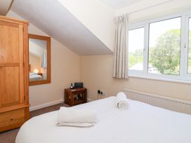 A bedroom with a bed with towels on it a wooden wardrobe a mirror and a window at Moorside in Horrabridge near Tavistock