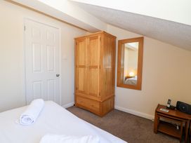A bedroom with a wooden wardrobe a mirror on the wall a bed with rolled towels and a small table with a phone and speaker at Moorside in Horrabridge near Tavistock