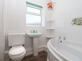 A bathroom with a toilet sink and bathtub with corner shelves and a small window at Moorside in Horrabridge near Tavistock