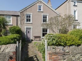 A stone pathway leading to a cottage entrance with a purple door surrounded by bushes and a stone wall at Trevor Cottage in Llandudno
