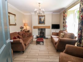 A living room with two brown sofas a fireplace a chandelier and floral curtains at Trevor Cottage in Llandudno