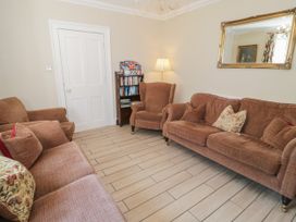 A living room with brown sofas cushions a floor lamp bookshelf and a mirror at Trevor Cottage in Llandudno