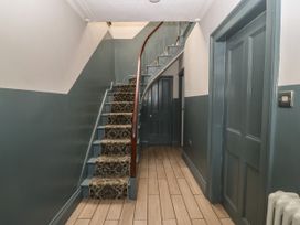 A hallway with a staircase with patterned carpet and blue doors at Trevor Cottage in Llandudno