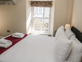 A bedroom with a bed towels on bed near a window and a lamp at Trevor Cottage in Llandudno