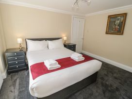 A bedroom with a double bed two bedside tables with lamps and a painting on the wall at Trevor Cottage in Llandudno