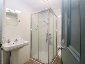 A bathroom with a shower enclosure a pedestal sink a mirror and a toilet at Trevor Cottage in Llandudno