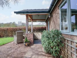 An outdoor porch with a chair and plants at The Lodge, Lower Trefedw near Abergavenny