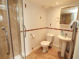 A bathroom with a shower, toilet, sink, and mirror at Hayloft Cottage in Bolton Low Houses
