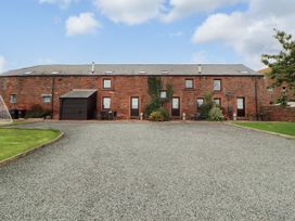 An outdoor area with a building, garage, and seating at Hayloft Cottage in Bolton Low Houses