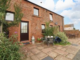 An outdoor area with a stone wall and seating at Horseshoe Cottage in Bolton Low Houses
