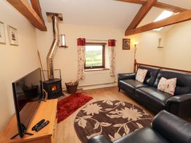 A living room with a sofa and wood stove at Horseshoe Cottage in Bolton Low Houses