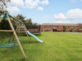 An outdoor play area with a swing set and trampoline at Horseshoe Cottage in Bolton Low Houses