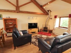 A living room with a sofa, television and wood stove at Horseshoe Cottage Bolton Low Houses