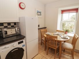 A kitchen with a washing machine and dining table at Garth Cottage in Haverfordwest