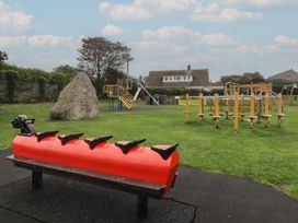 A playground with equipment including a slide and swings at Garth Cottage in Haverfordwest