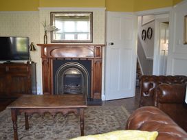 A living room with a wooden fireplace centered below a mirror and a wooden table in front at Lily House in Minehead