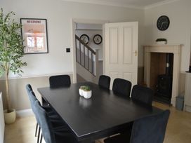 A dining room with a black table and chairs a potted plant on the table a fireplace a wall clock and a framed picture at Lily House in Minehead