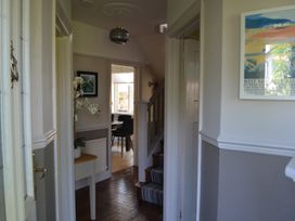 A hallway with a small table and white orchid leading to a dining room and staircase at Lily House in Minehead