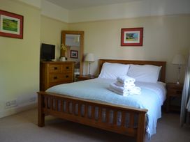 A bedroom with a wooden bed with folded towels on it and wooden furniture at Lily House in Minehead