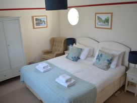 A bedroom with a double bed with blue and white pillows and towels on the bed a beige armchair a white wardrobe and nightstands with blue lamps at Lily House in Minehead