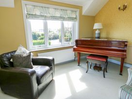 A snug with a piano and an armchair at Bryn y Don in Benllech