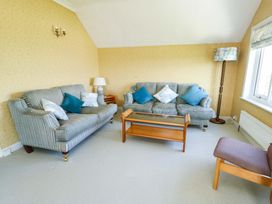 A living room with a sofa, chair, and coffee table at Bryn y Don in Benllech