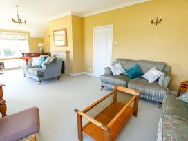 A living room with a piano, sofas, coffee table, and lamp at Bryn y Don in Benllech