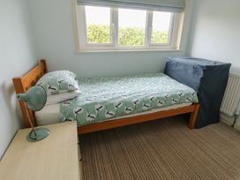 A bedroom with a bed and a bedside lamp at Bryn y Don in Benllech
