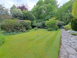 A garden with grass a stone path and various bushes and trees at West Ridge in Boscombe
